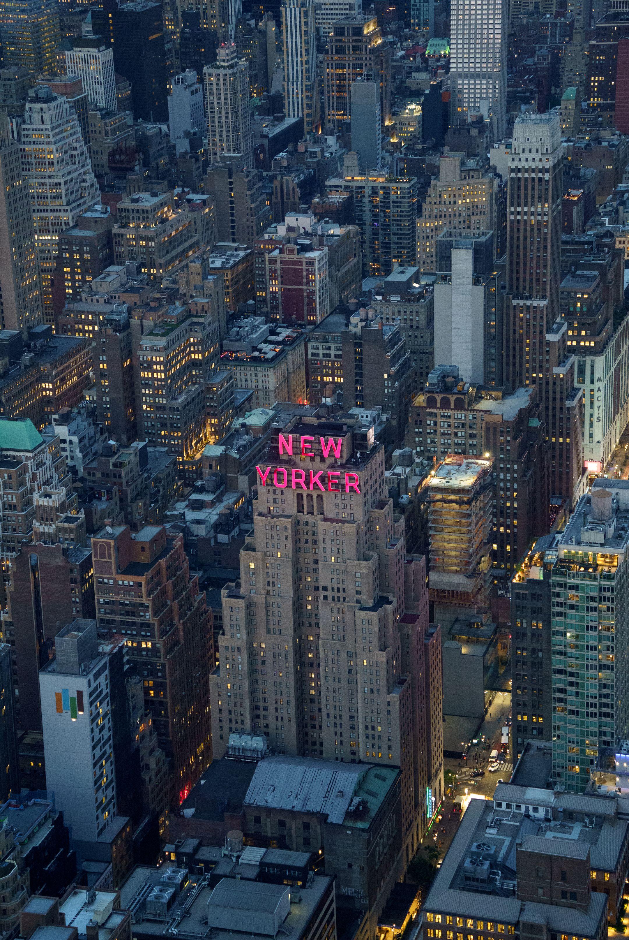 A breathtaking aerial shot showcasing the illuminated buildings of New York City, featuring the iconic New Yorker Hotel.