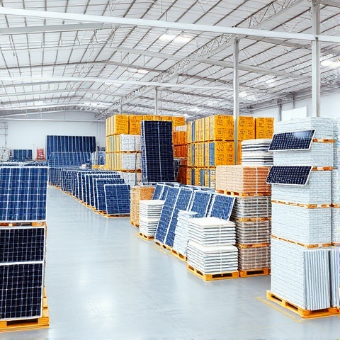 Large organized solar equipment warehouse with bulk inventory and stacked solar panels