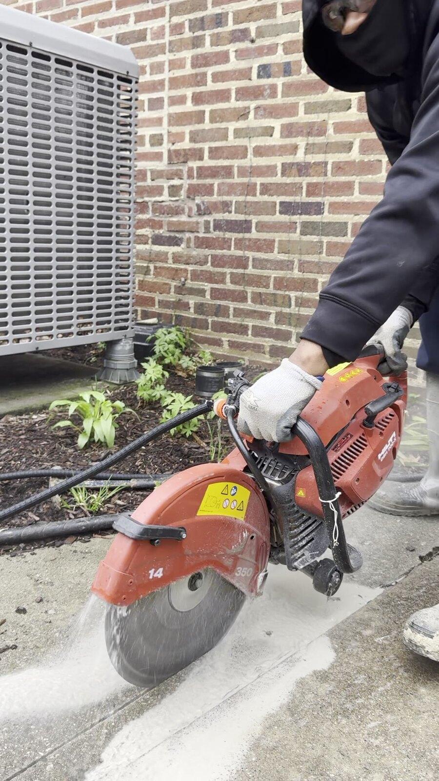 Technician cutting concrete for a Metro Detroit drainage improvement