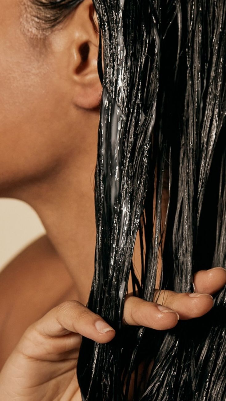 Close-up of a stylist working product through wet hair.