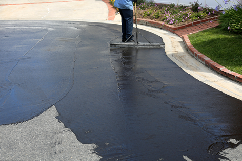 A Pavement Transformations worker sealcoating asphalt.