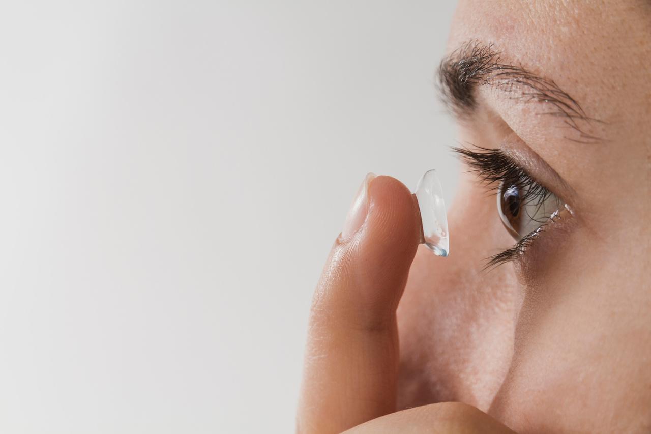woman inserting a contact lens in her eye