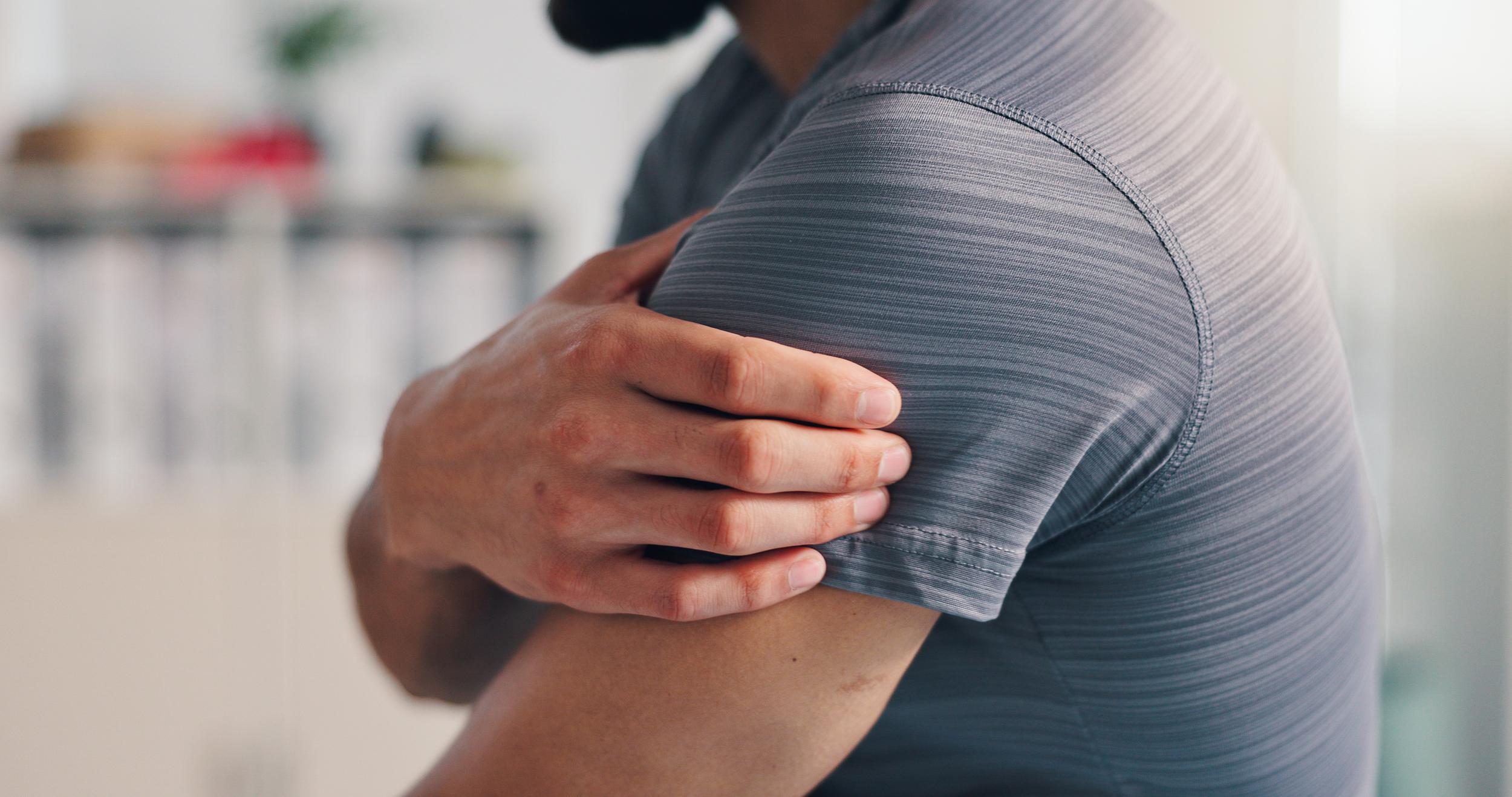 man-massaging-aching-shoulder-in-bright-room-2026-03-25-03-46-04-utc.jpg