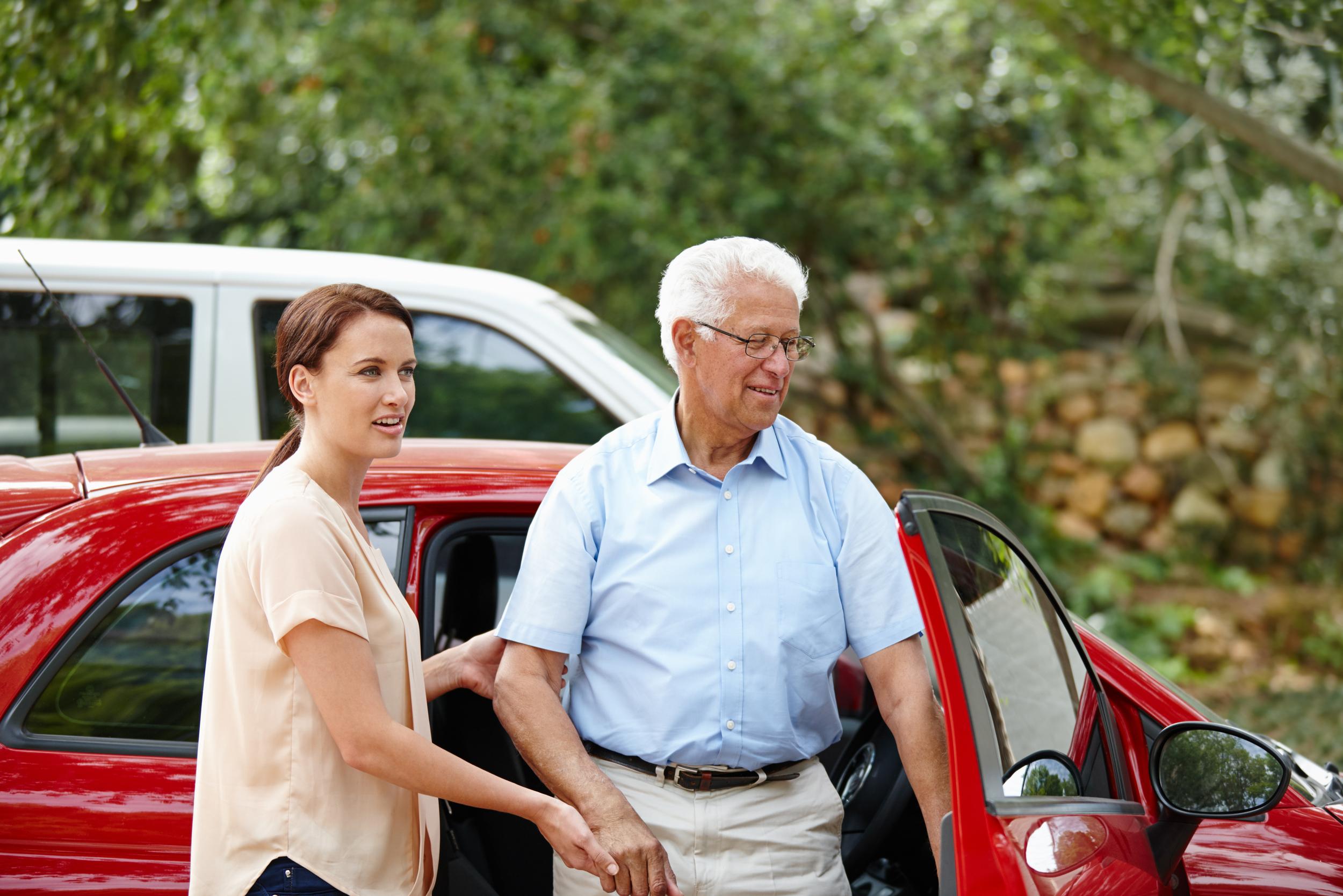 smiling-woman-assists-senior-man-getting-out-of-ca-2026-03-25-02-58-08-utc.jpg