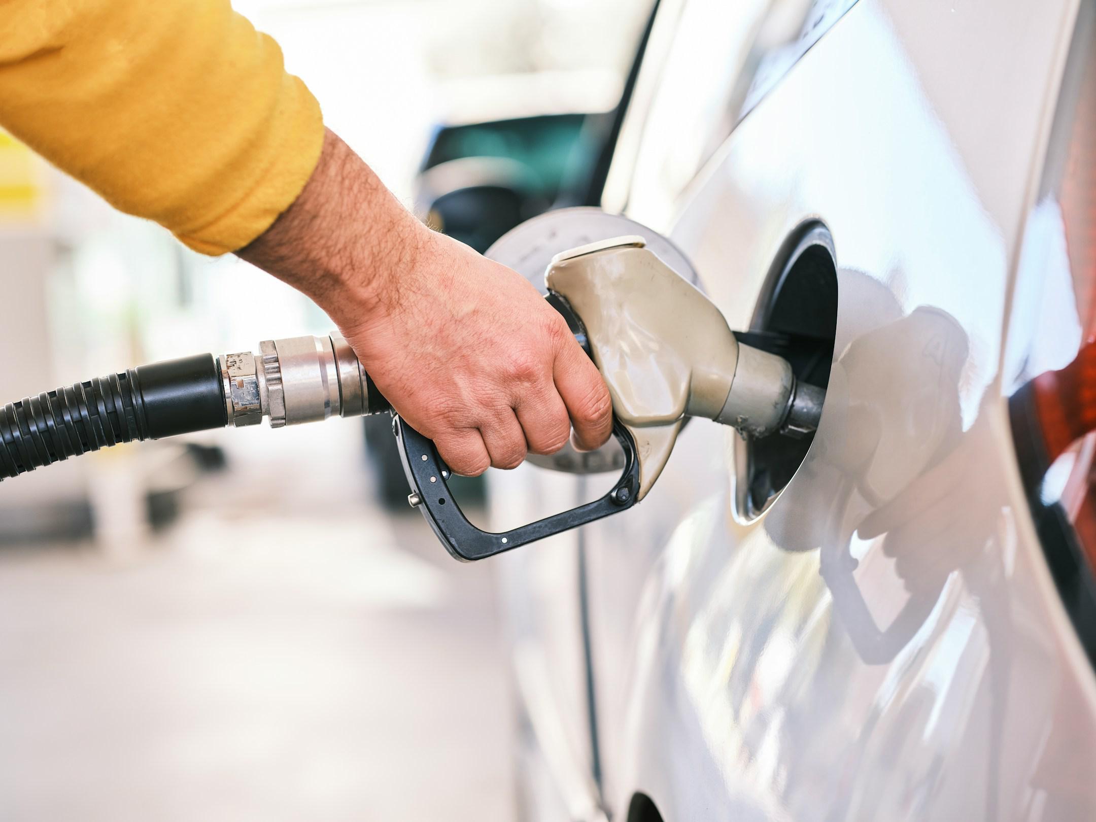 Pumping gas at gas pump. Closeup of man pumping gasoline fuel in car at gas station.