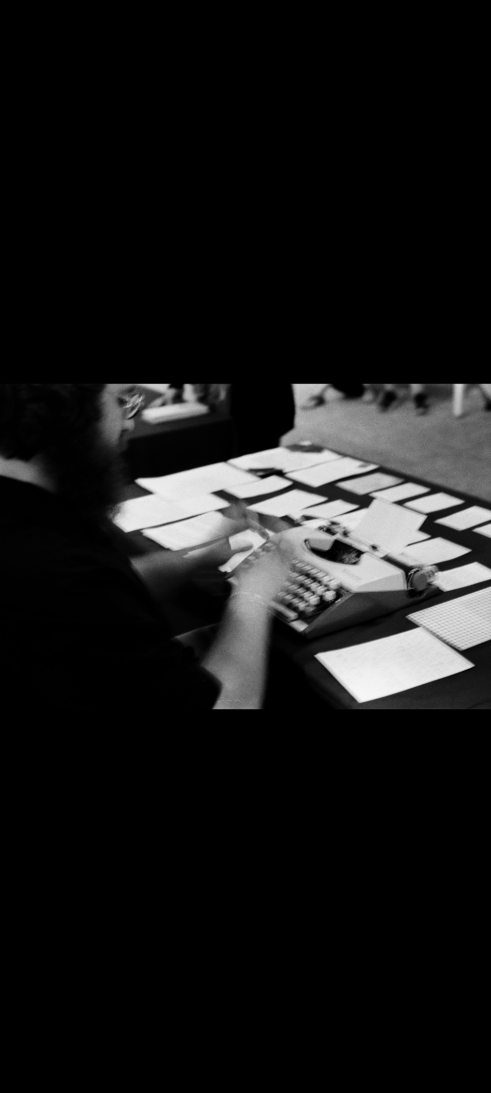 Black-and-white film photograph of Chris writing on a typewriter