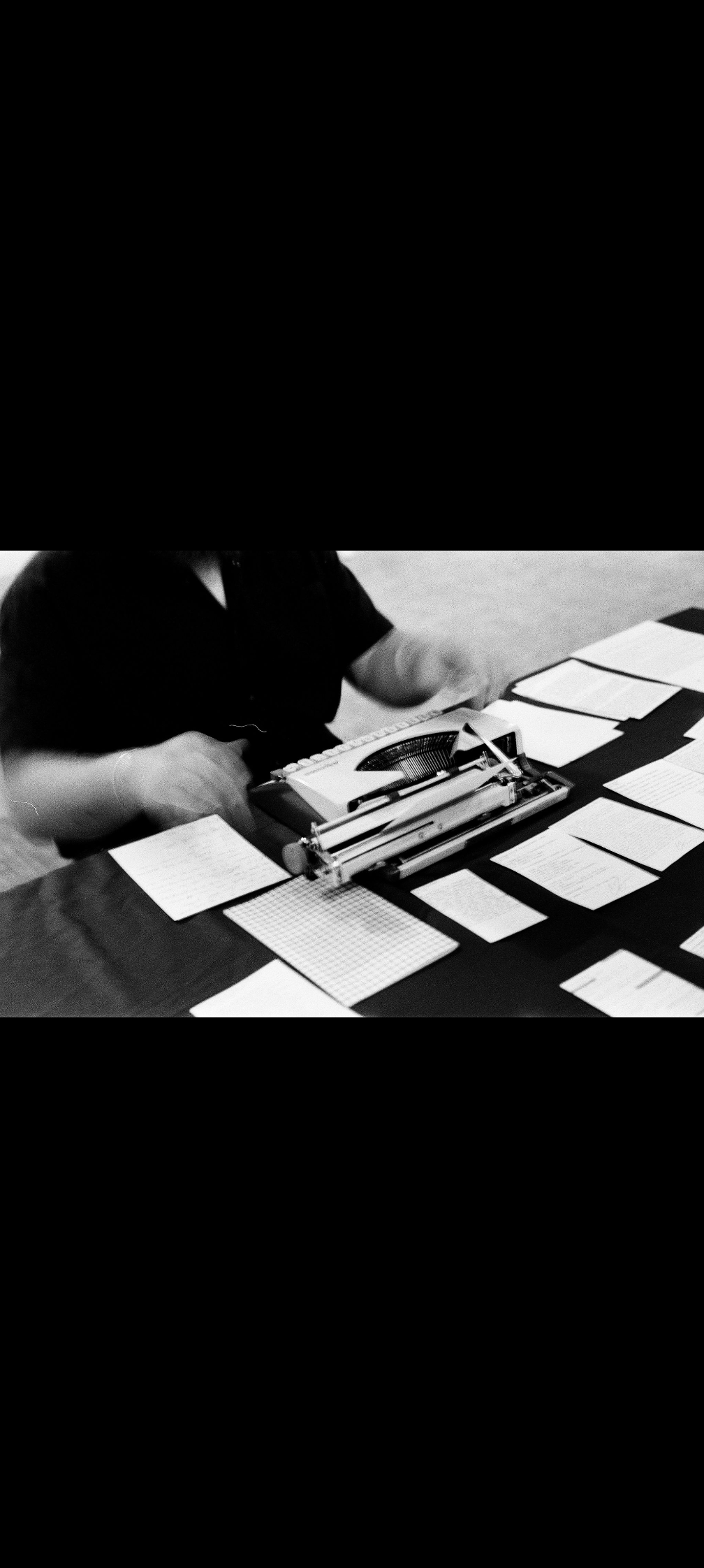 Black-and-white film detail of the typewriter and poems on the table