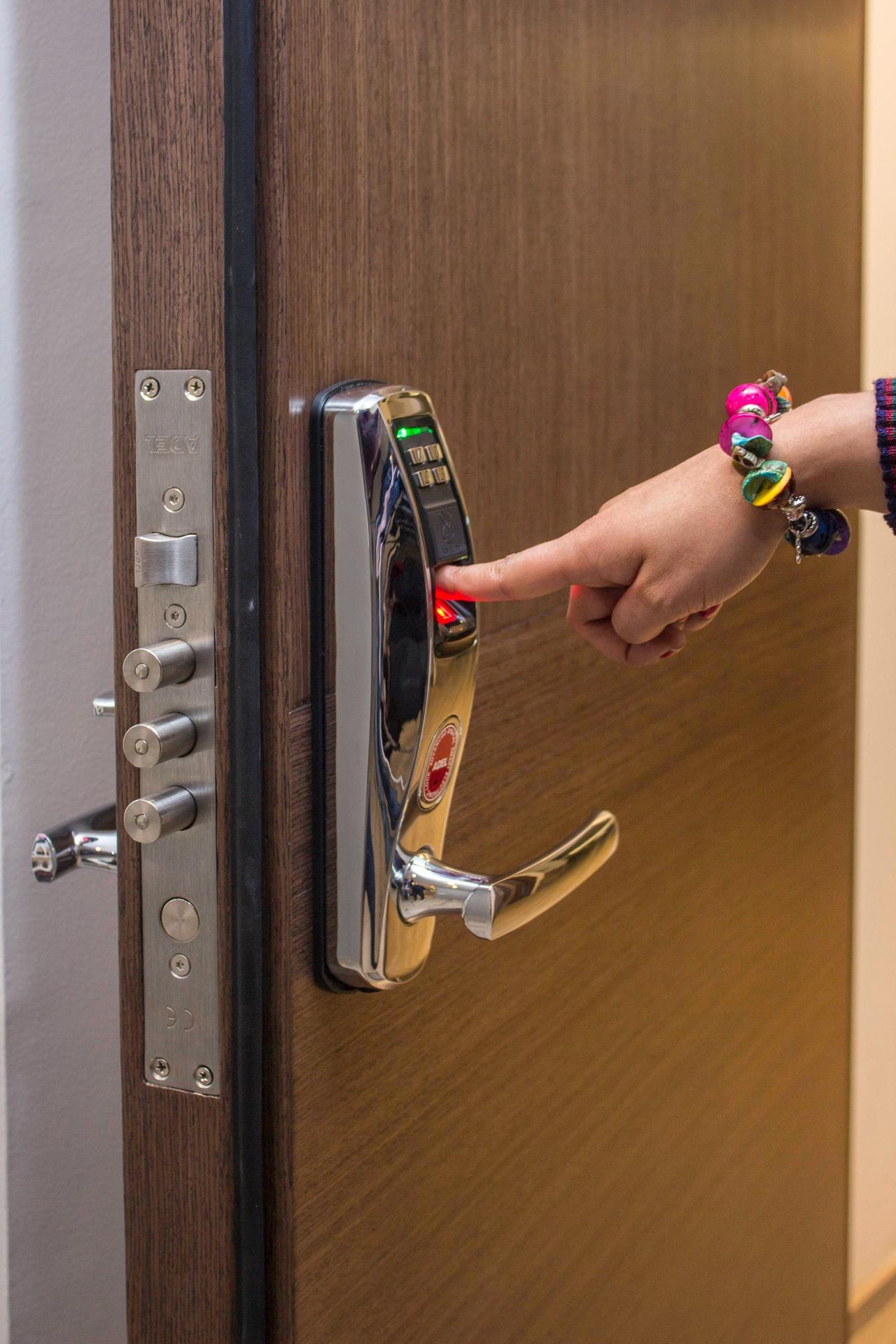 A hand using fingerprint access on a digital security door lock, enhancing safety.