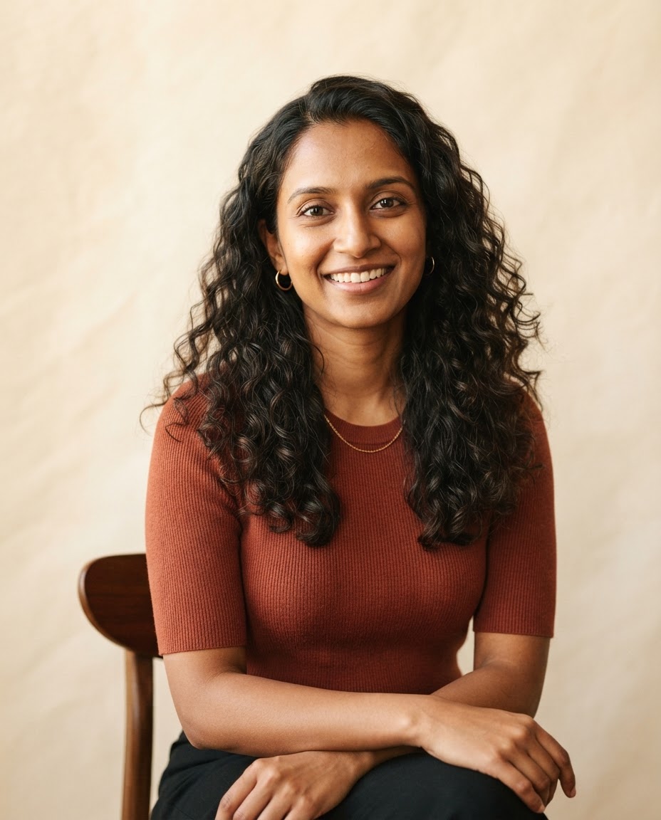 Priya Nanduri, South Asian woman with long dark curls wearing a terracotta knit top.