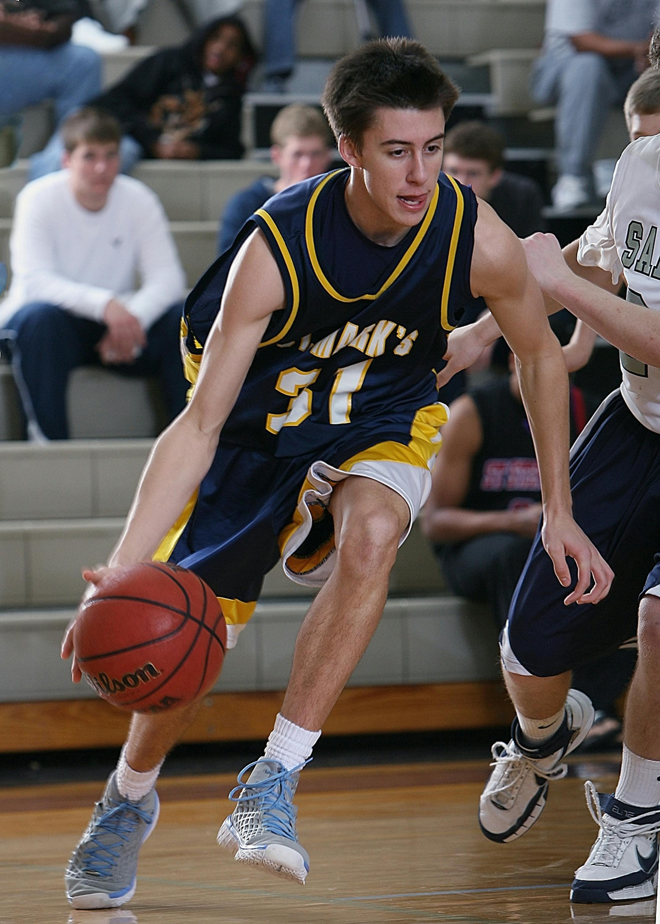Teen basketball player dribbling during an intense game in a school gym.