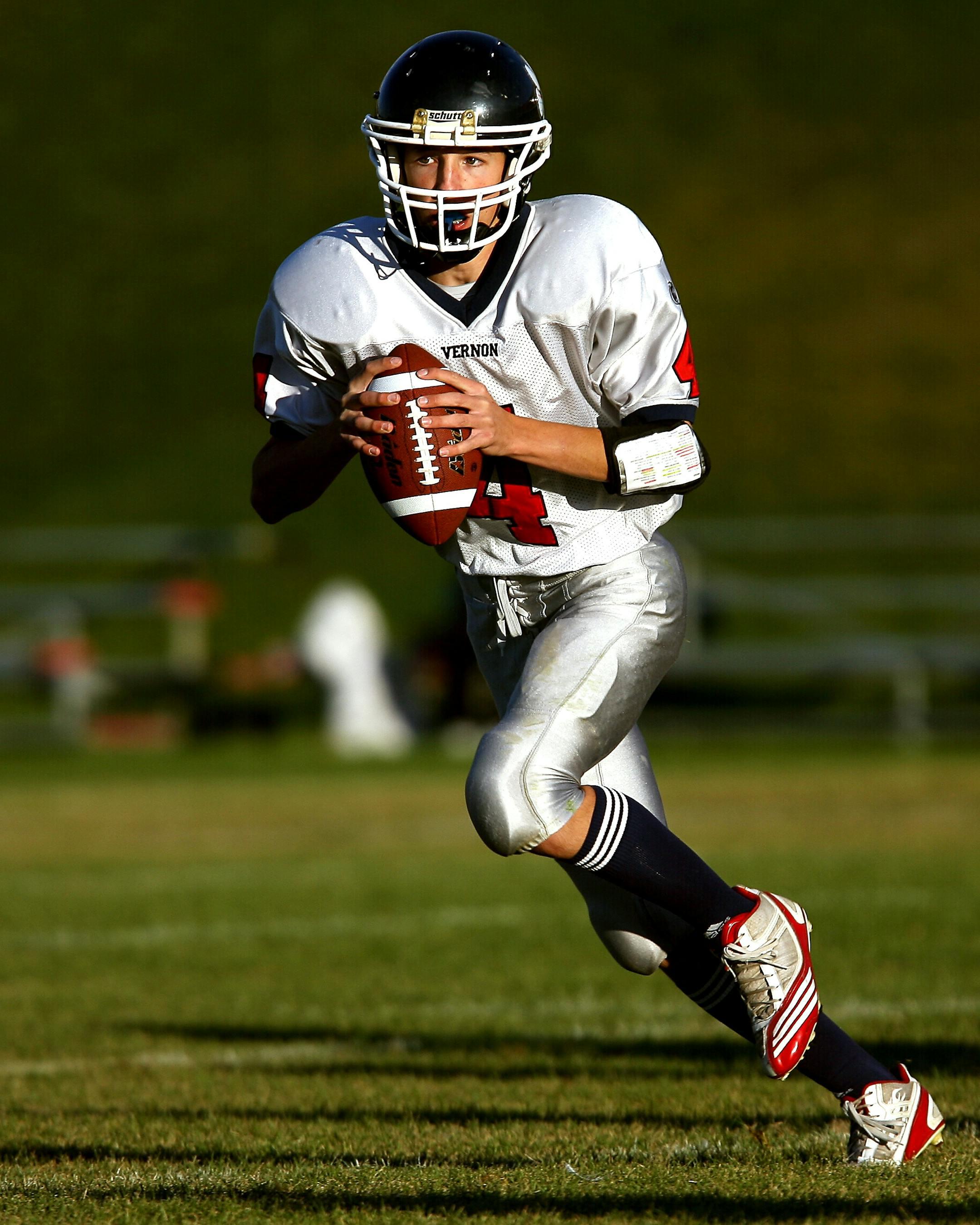 A focused young athlete playing quarterback during a daytime football game.