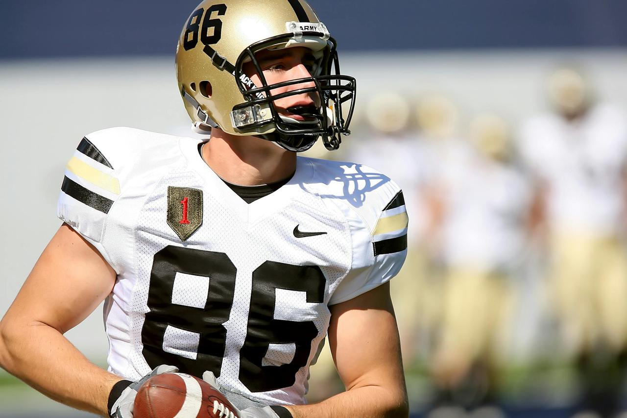 Focused college football player in uniform holding a football during a game.