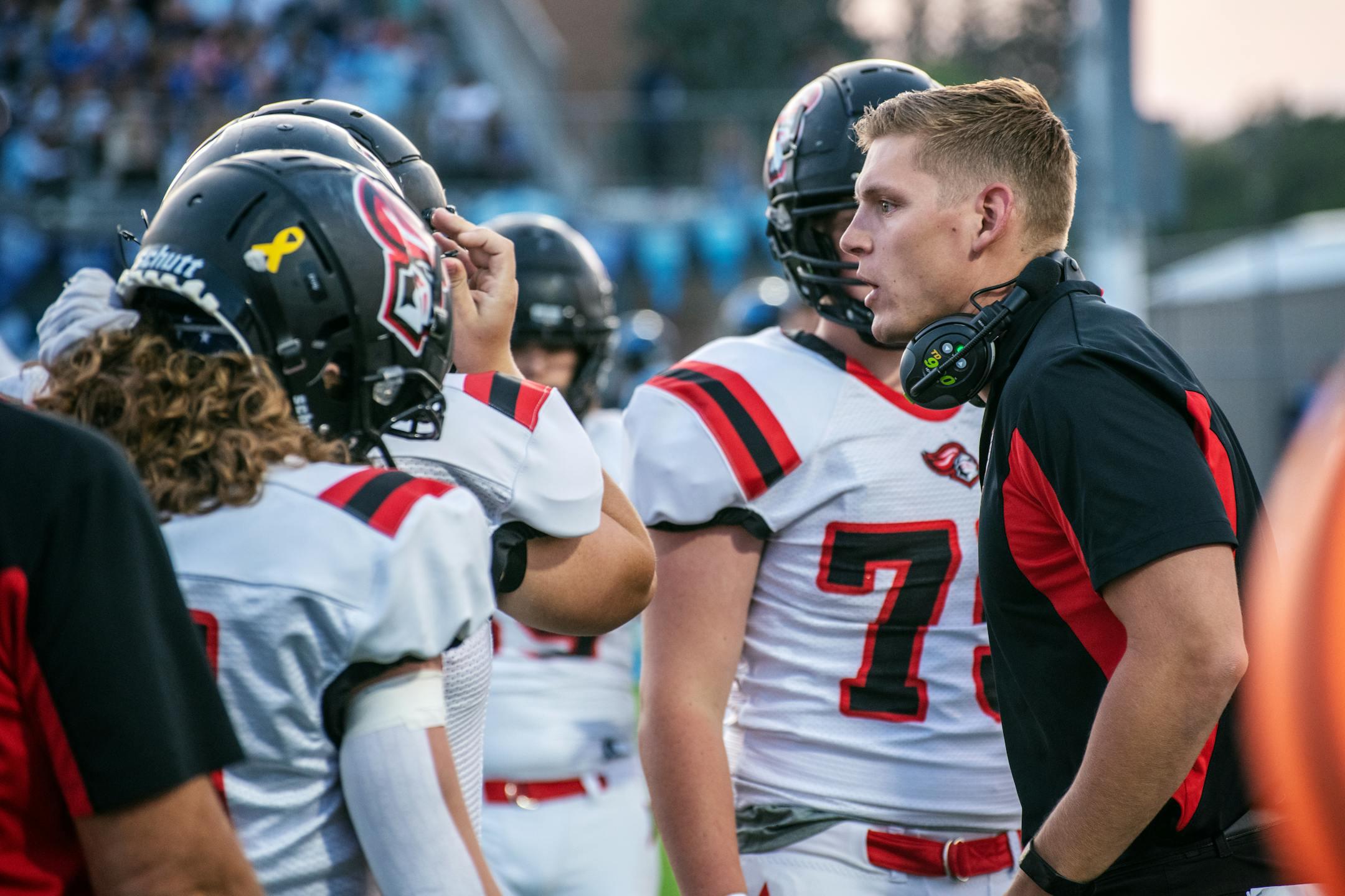 Football coach motivating players on field during a game in Idaho Falls.