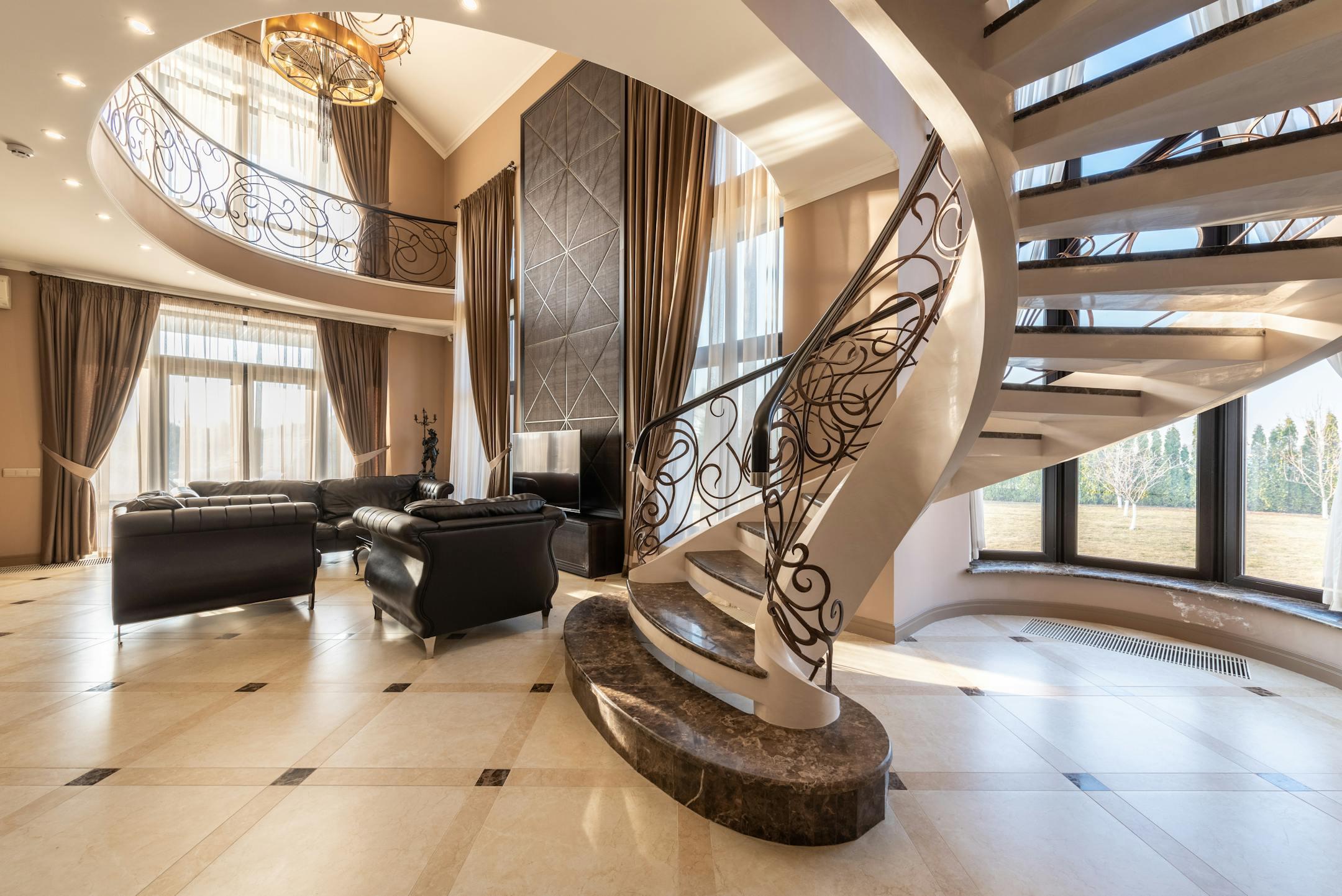 Elegant modern living room featuring a grand spiral staircase and luxurious decor.