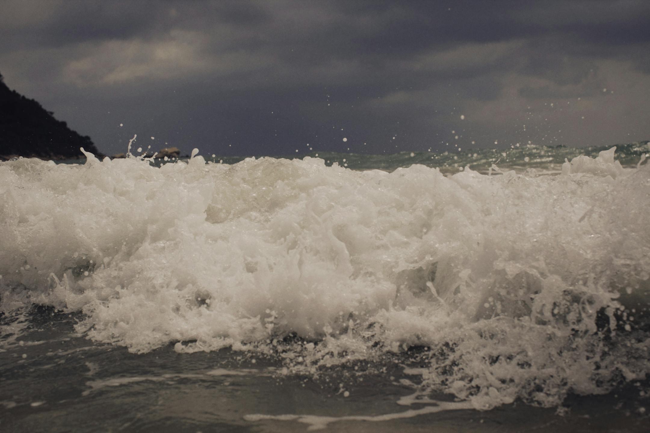 Close-up of powerful ocean waves crashing under a stormy sky, showcasing nature's strength.
