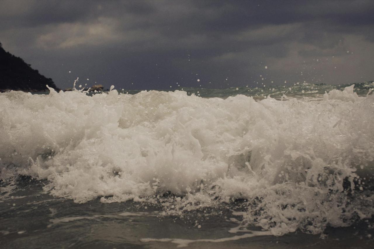 Close-up of powerful ocean waves crashing under a stormy sky, showcasing nature's strength.