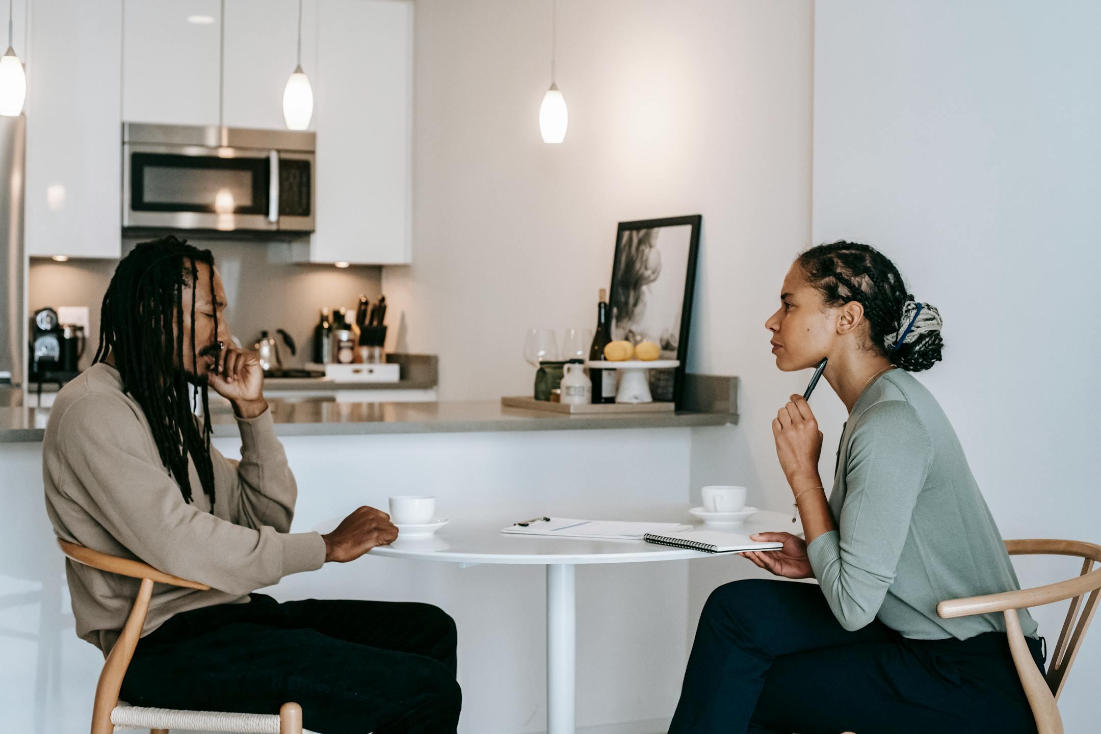 A focused therapy session between a consultant and client discussing mental health indoors.