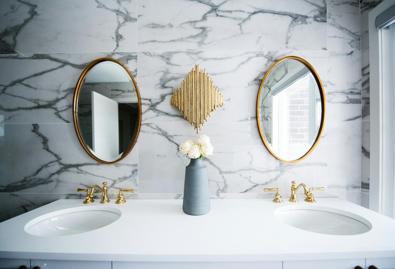 Bright marble and gold bathroom with two sinks and two mirrors.