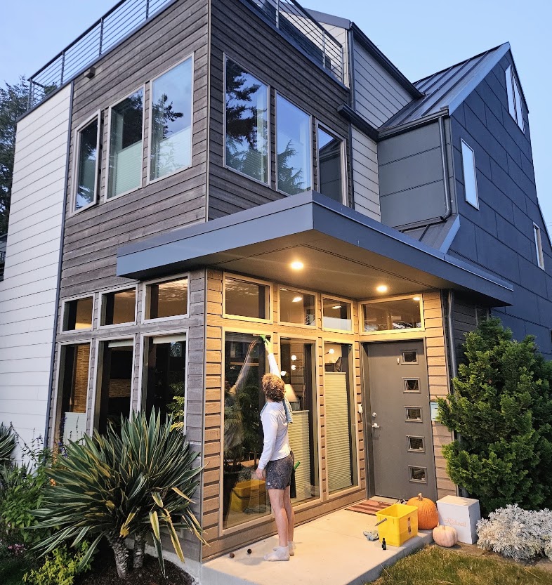 Person cleaning exterior windows at a multi-story home