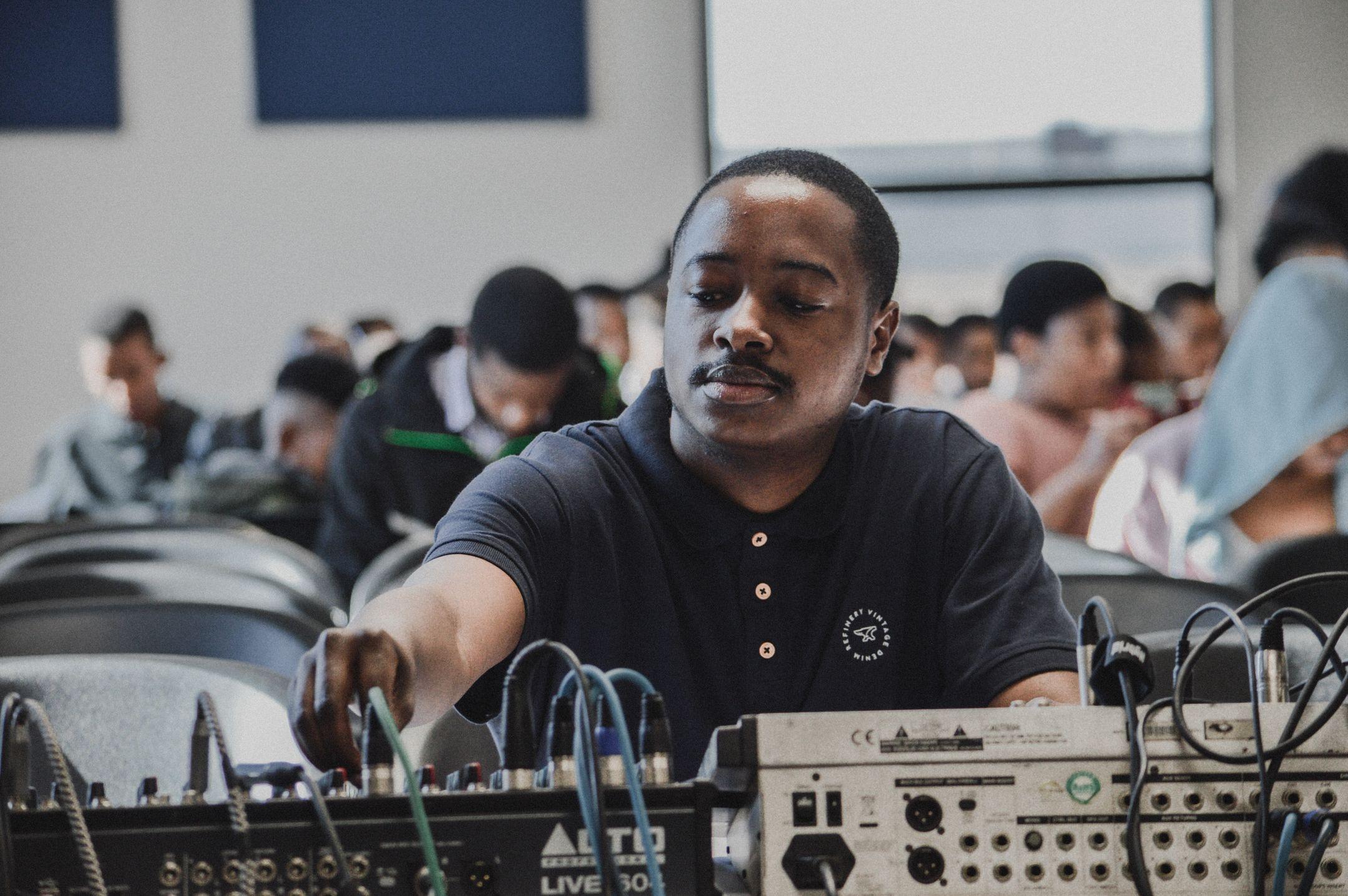 Man adjusting audio equipment in a classroom setting during a training session.