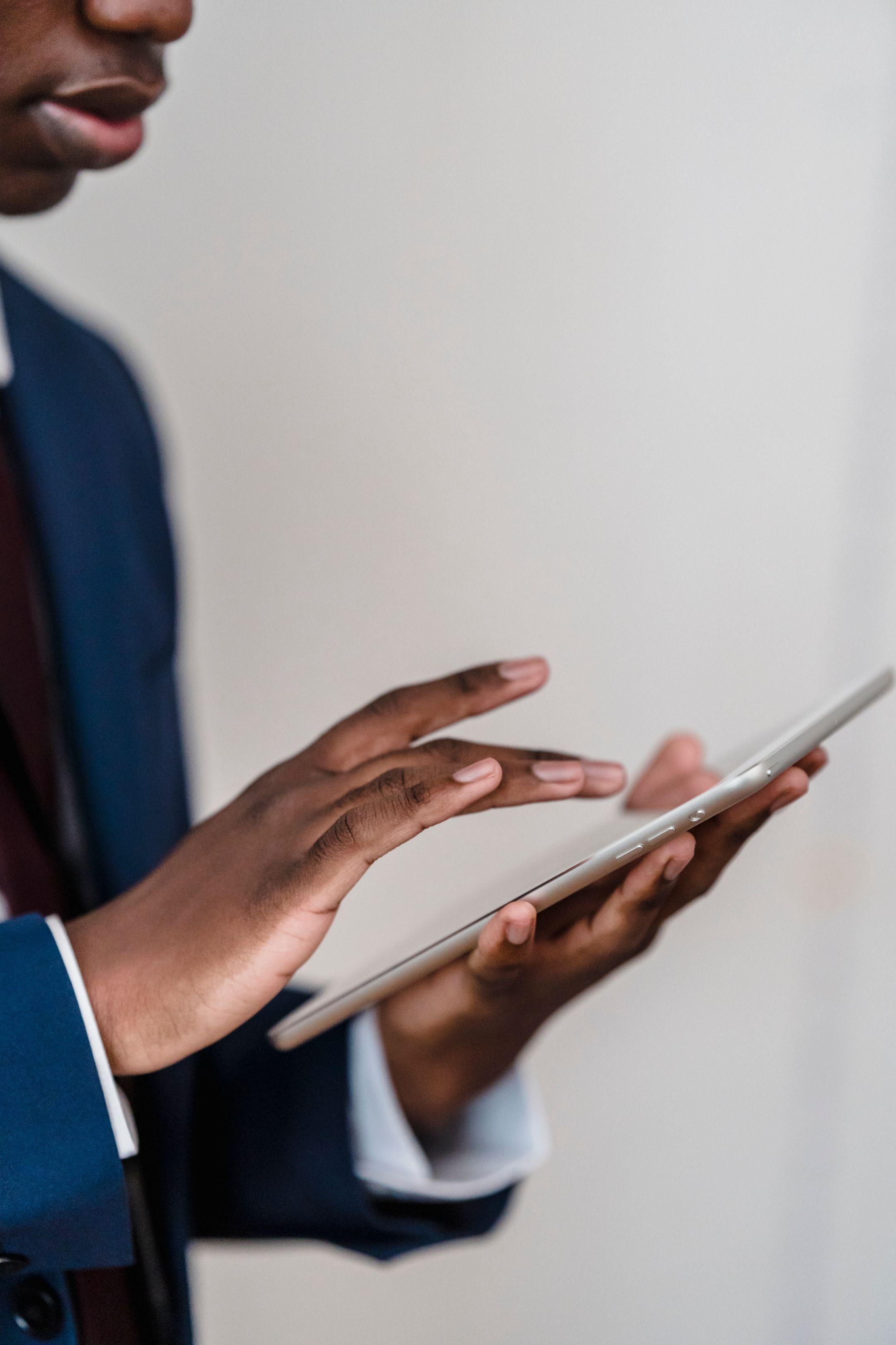 Close-up of a businessman's hands using a digital tablet indoors.
