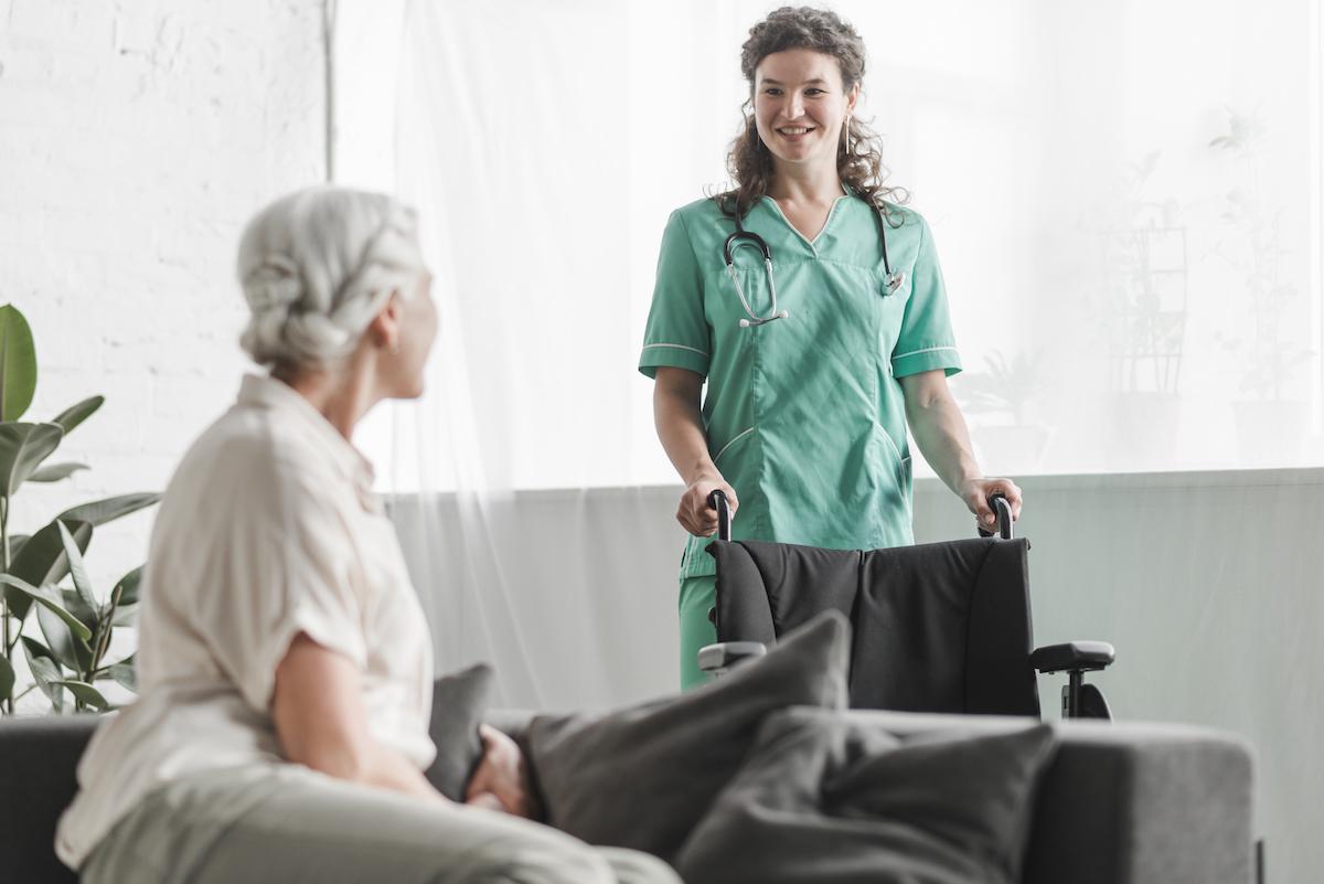 senior-woman-looking-smiling-female-nurse-with-wheelchair.jpg