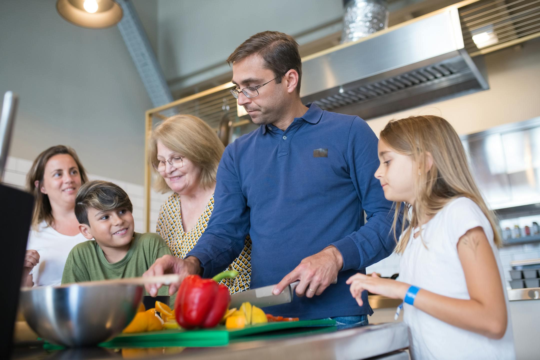 A happy family bonding in the kitchen while preparing a meal together indoors.