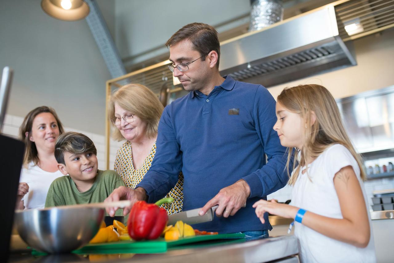 A happy family bonding in the kitchen while preparing a meal together indoors.