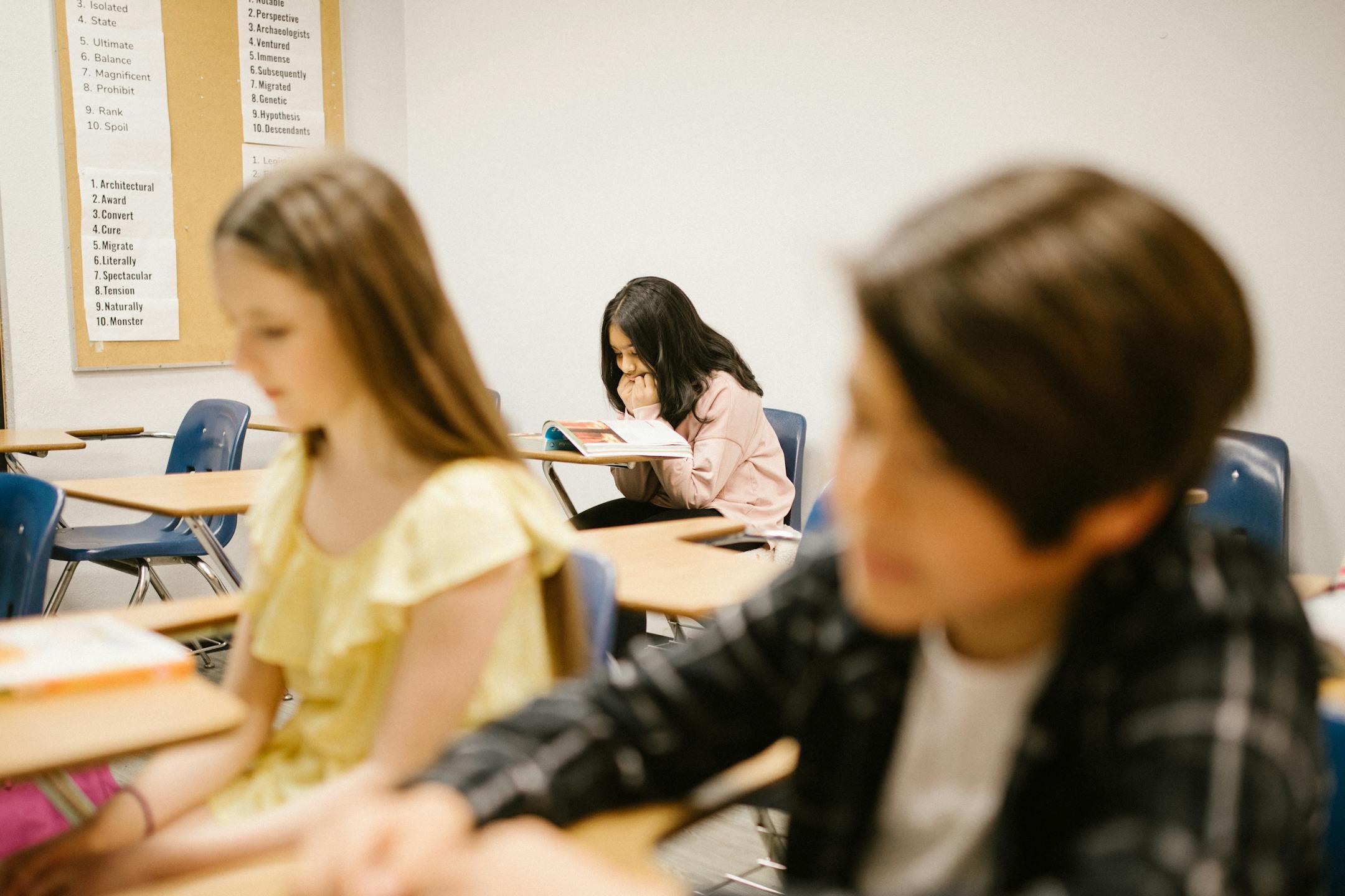 A student sits alone in a school classroom, depicting solitude and contemplation.
