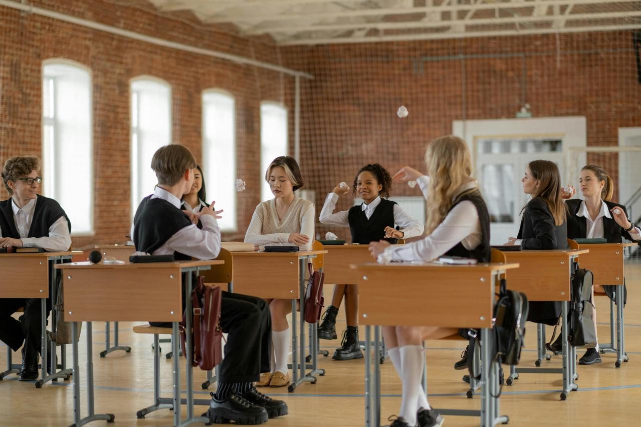 A diverse group of students wearing uniforms interacting in a classroom, emphasizing school life and education.