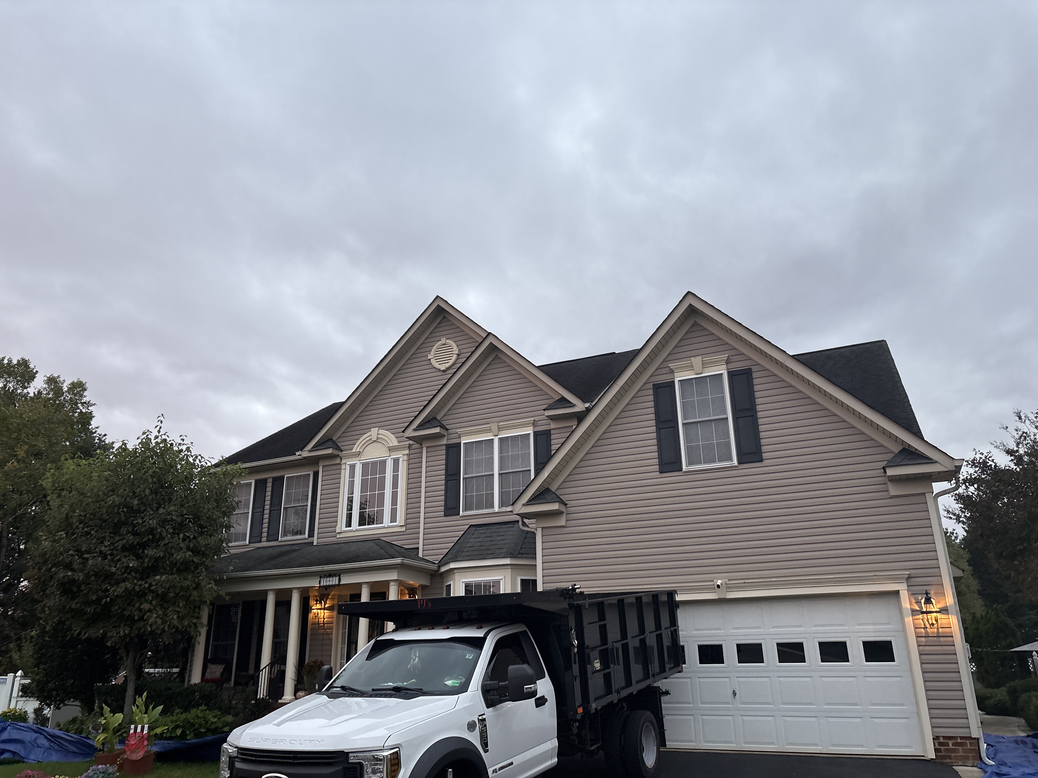 Home with a completed roof replacement and a dump truck in the driveway