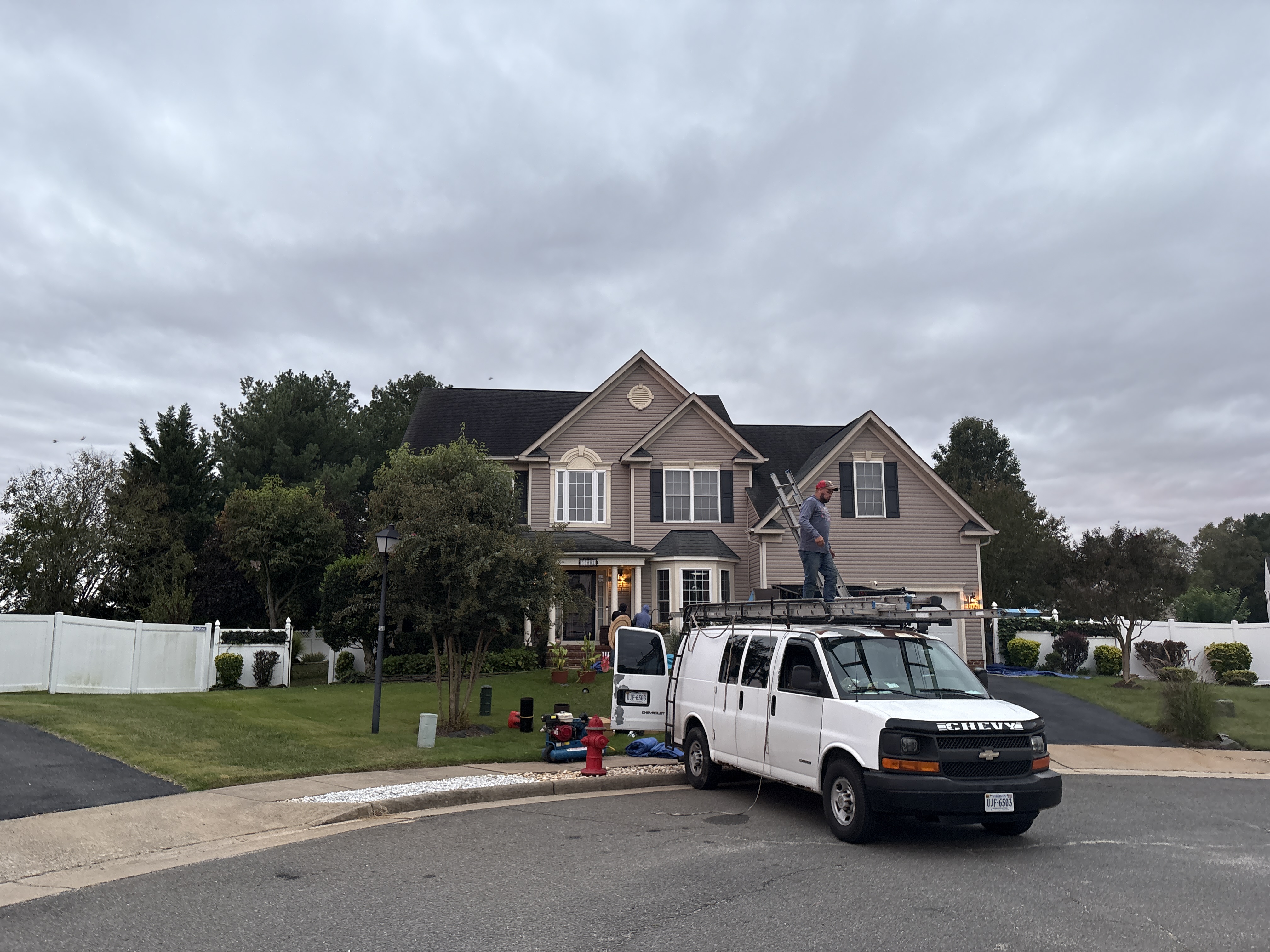 Technician on a ladder working on a home's roof