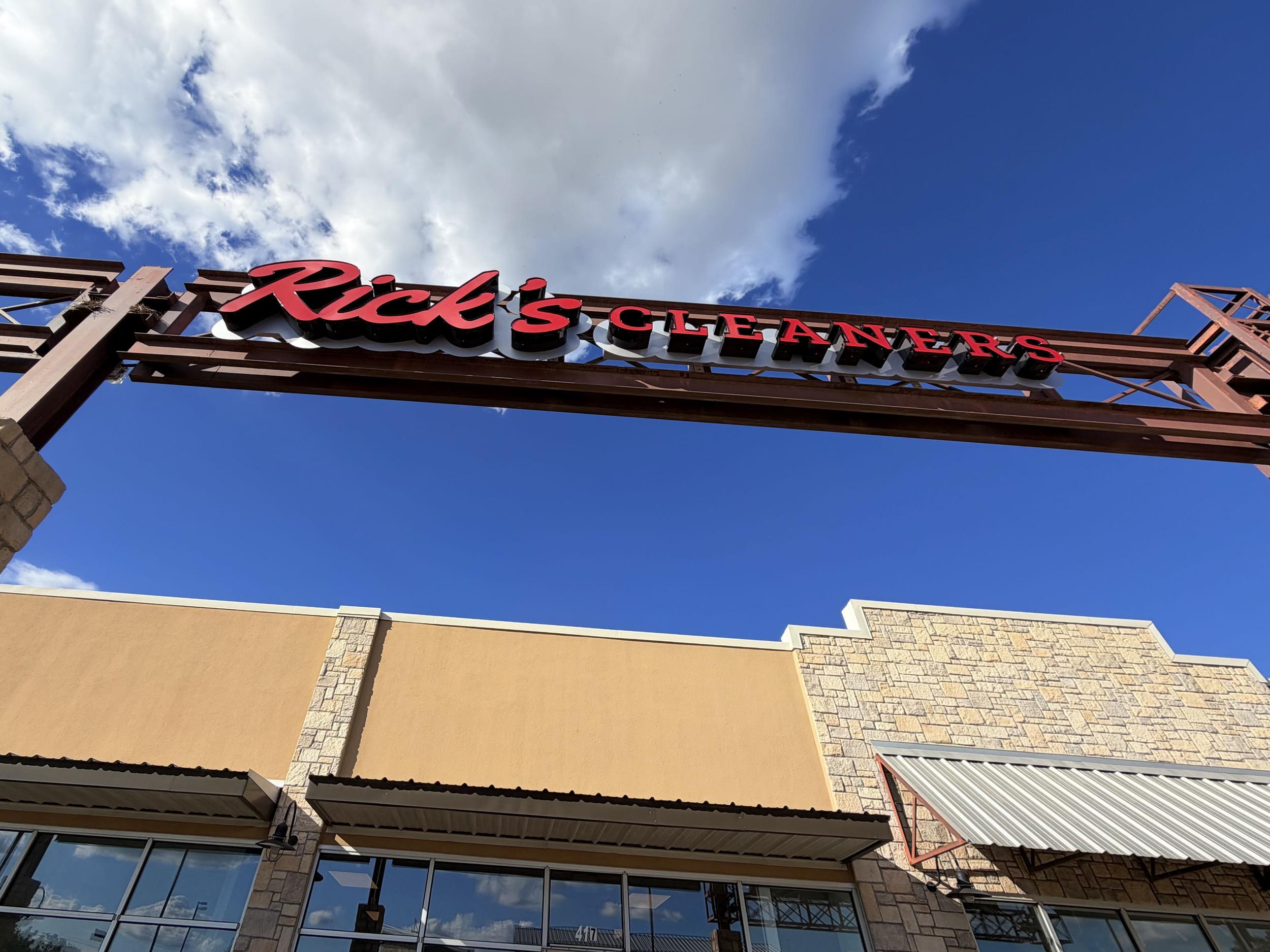 Rick's Cleaners Dripping Springs red storefront sign against blue sky