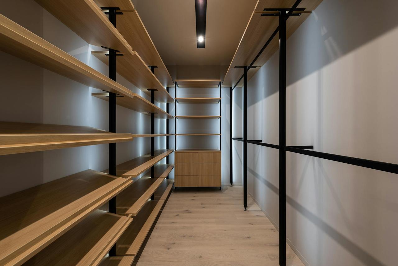 Explore a spacious modern walk-in closet with wooden shelves and sleek design, perfect for organizing.