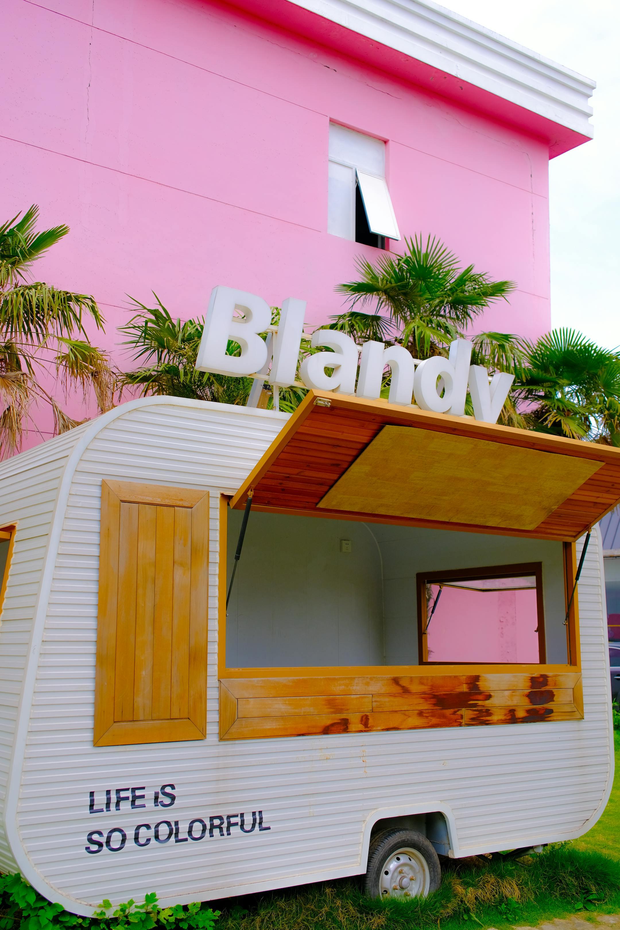 Bright pop-up shop with a vibrant pink backdrop and palm trees, embodying a lively atmosphere.