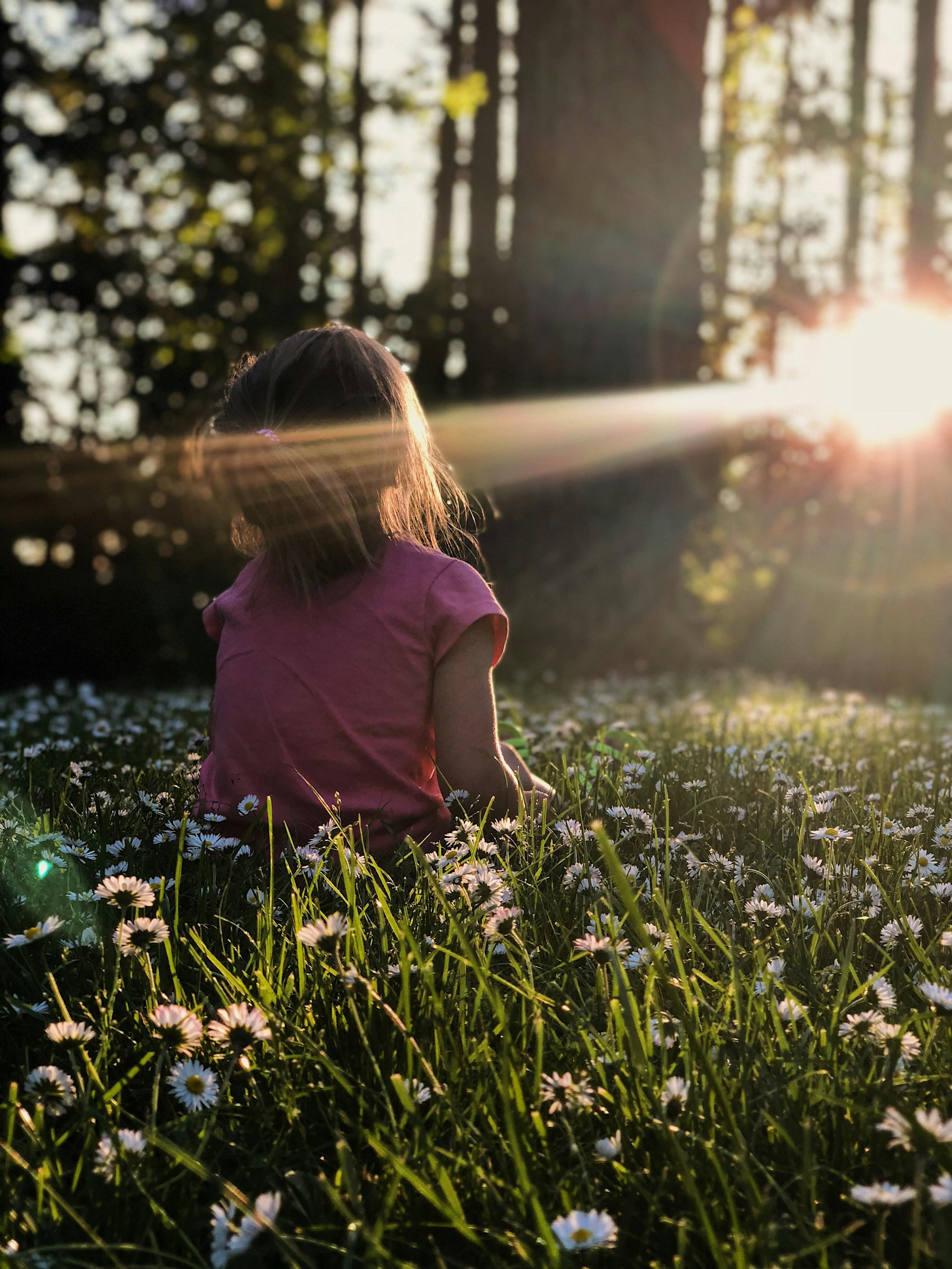 My family was enjoying some time on a hike in a wooded area.  The way the light was coming through the trees and across the grass and daisies was making me itch to capture the moment. 

I got down on my stomach in the grass to capture this photo of my daughter Ellie. All I had with me that day was my iPhone X which was still a champ for captuing the moment perfectly. I just love the way the end of the day sunlight was making her glow.  To me this photo perfectly captures summer, childhood, and my sweet gi