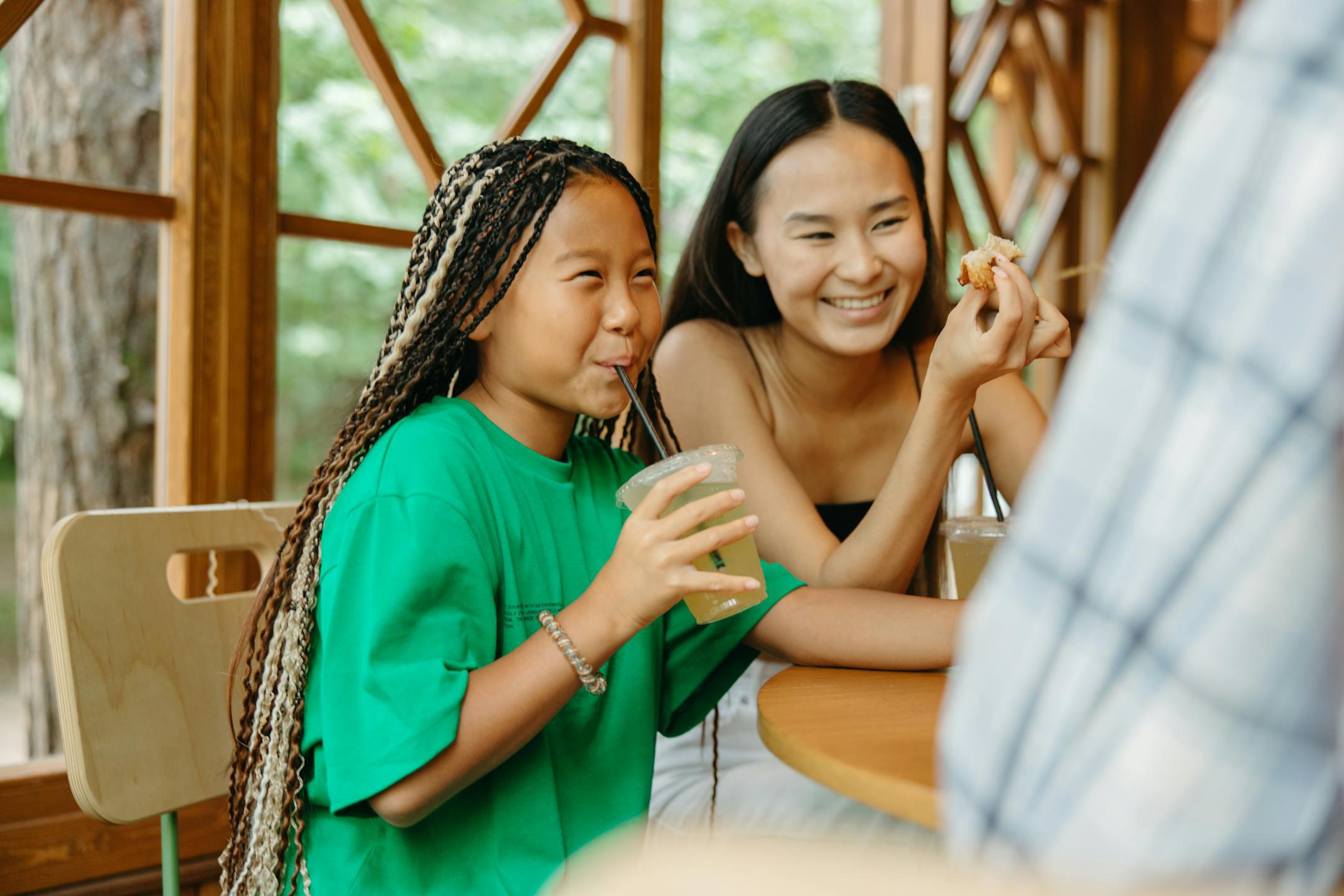 A mother and daughter enjoying a fun meal together in a bright café with wooden interior.