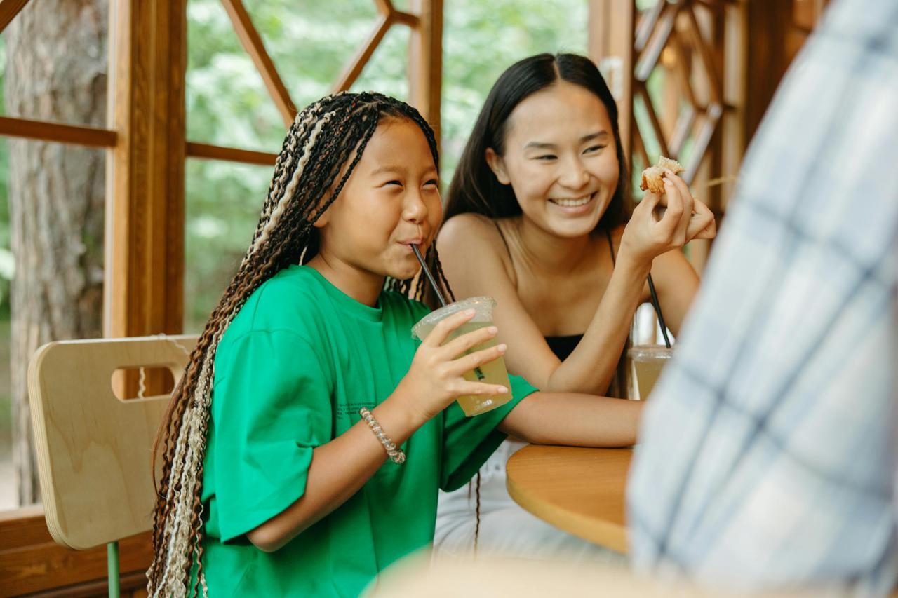 A mother and daughter enjoying a fun meal together in a bright café with wooden interior.
