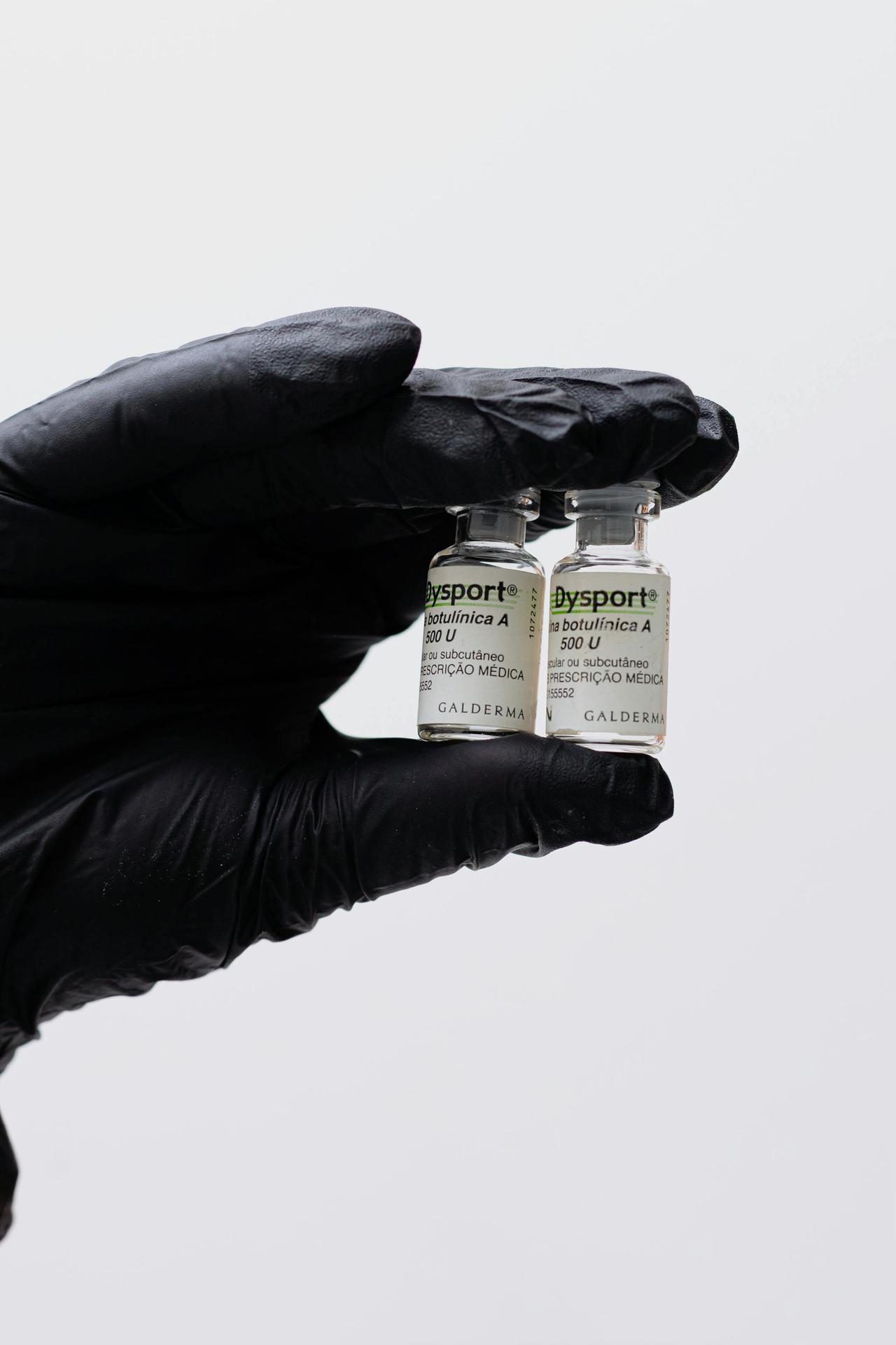 Close-up image of a gloved hand holding two Dysport botulinum toxin vials.