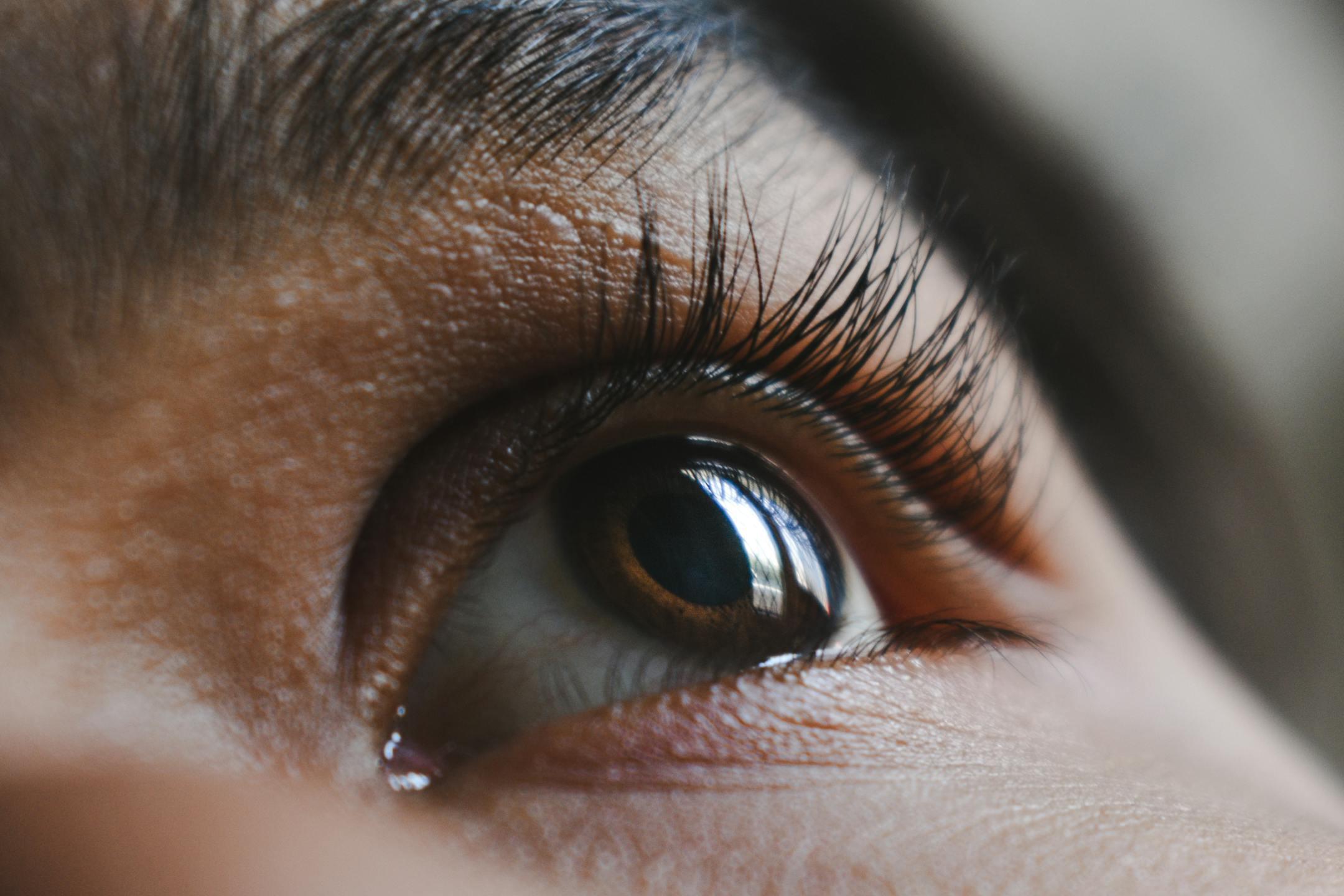 Macro shot of a human eye showcasing long eyelashes, iris detail, and reflection.
