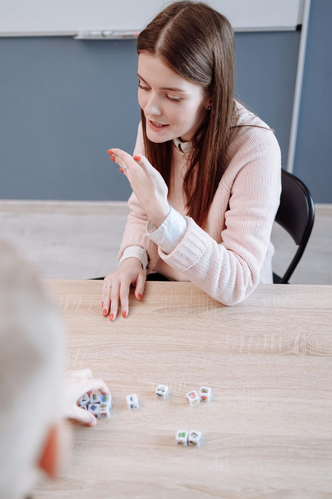 A young woman focuses on a dice game, displaying strategy and thoughtfulness indoors.