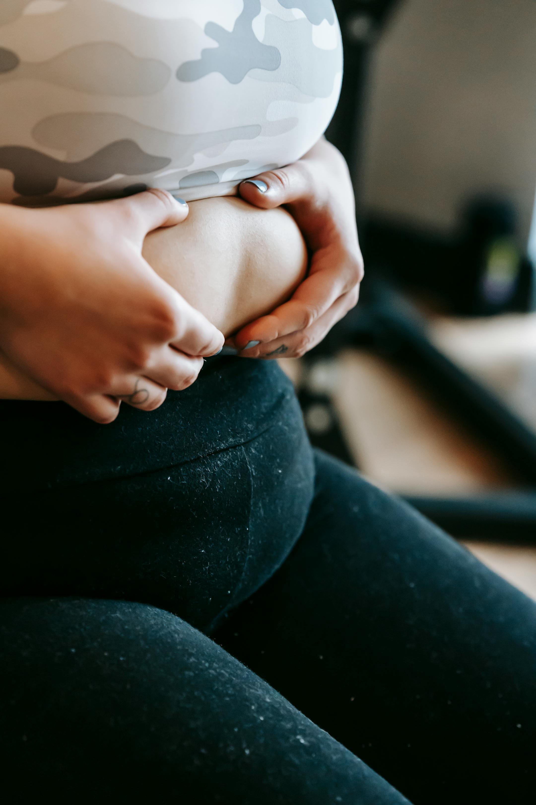 A woman in activewear holding her belly, emphasizing fitness and wellness.
