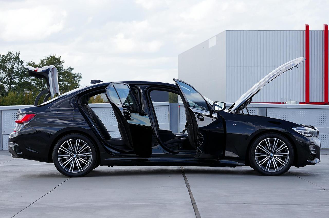 Black luxury sedan with doors and trunk open, parked on a rooftop parking area.