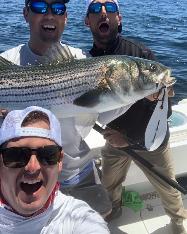 three men posing with a fish and smiling