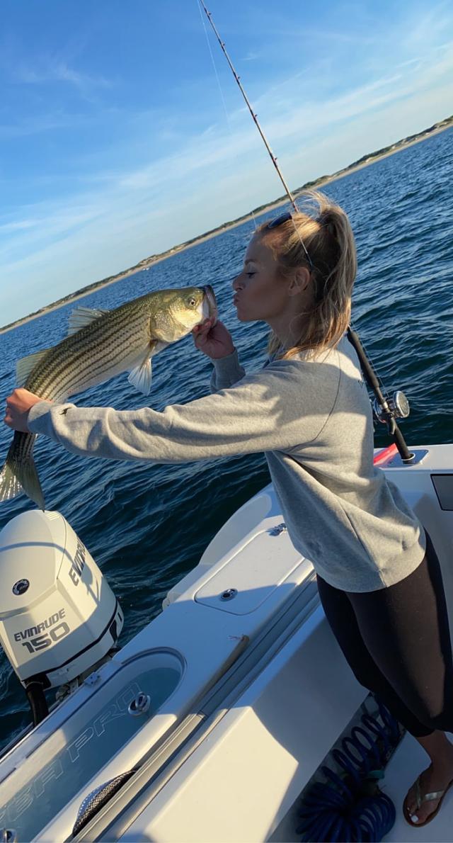 young lady pretending to kiss a fish she caught