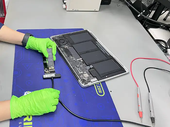 Laptop MacBook z wyjętym dyskiem Apple SSD oraz adapterem do diagnostyki na stole laboratoryjnym.
