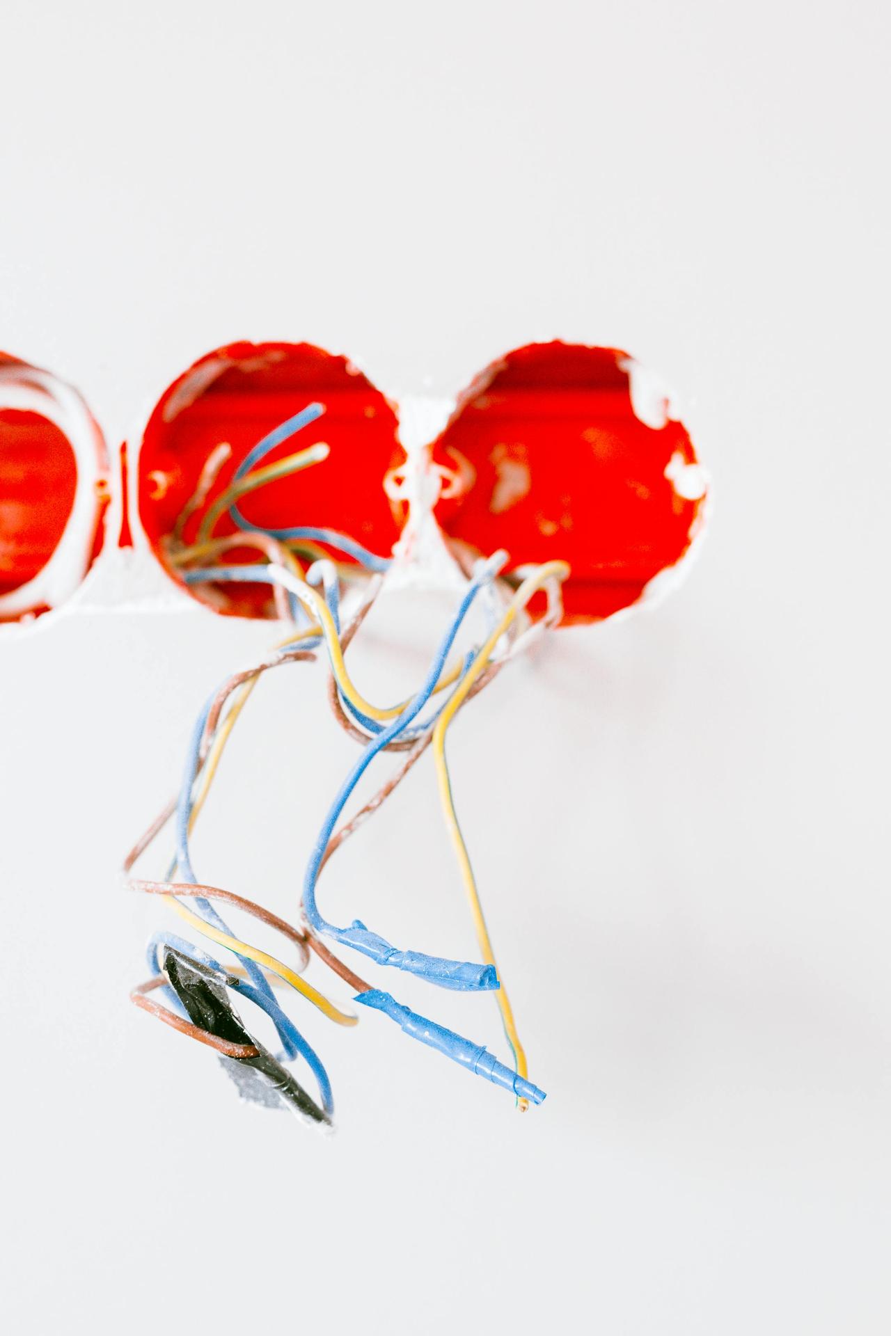 Vibrant electrical wires emerging from a socket during renovation work, showcasing home improvement.