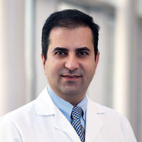 A man in a blue shirt and tie and doctor's coat.
