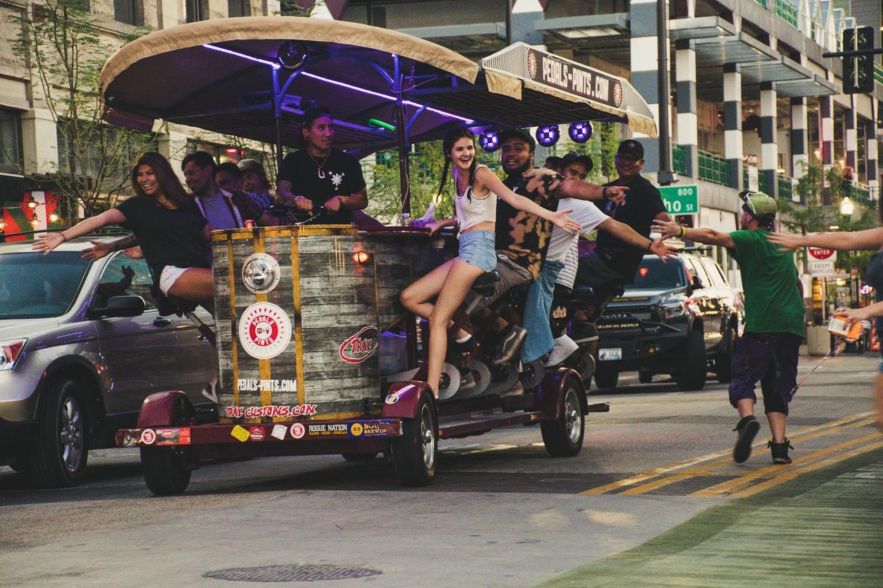 A lively group enjoys a pedal pub ride on an urban street, capturing joy and excitement.