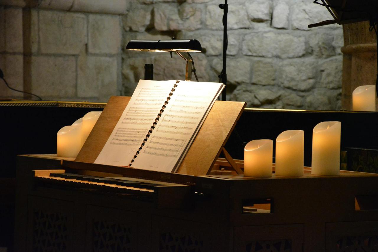 A dimly lit music stand with sheet music surrounded by glowing candles, creating a serene ambiance.